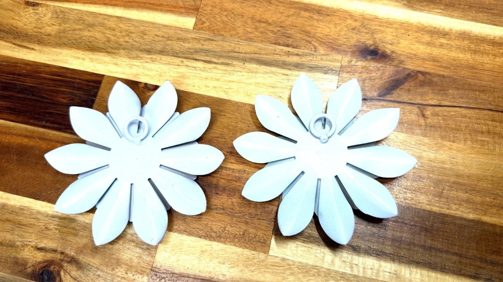Small, teal-colored metal wall art feature is a layered flower design with disti