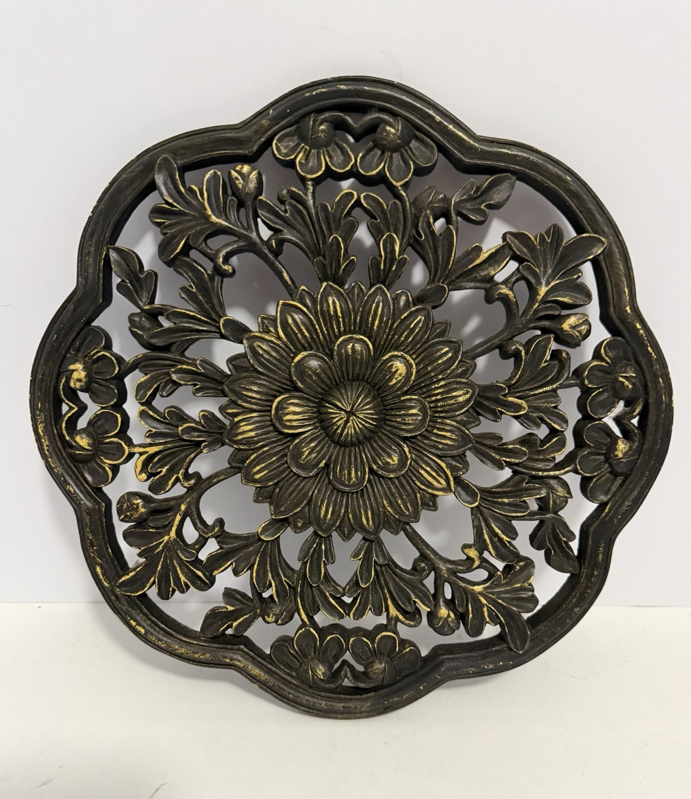 floral wall medallion featuring a black and gold patina finish